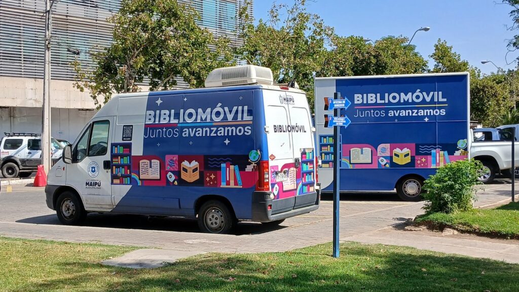 Dos vehículos de bibliomóvil estacionados, con sus costados abiertos como estanterías.